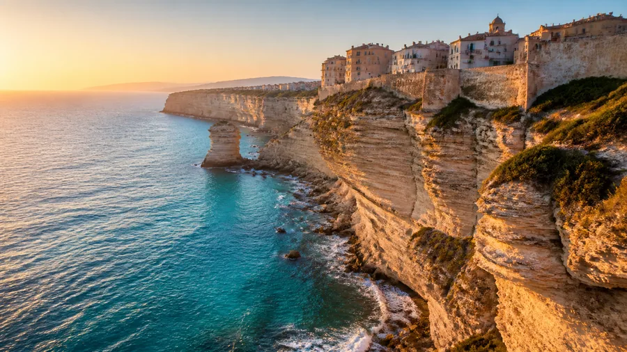 Ambiance romantique inspirée de Bonifacio avec falaises blanches, citadelle et mer turquoise au coucher du soleil