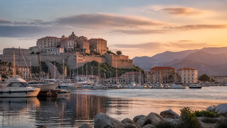 Ambiance romantique inspirée de Calvi avec citadelle, baie, voiliers et montagnes au soleil couchant